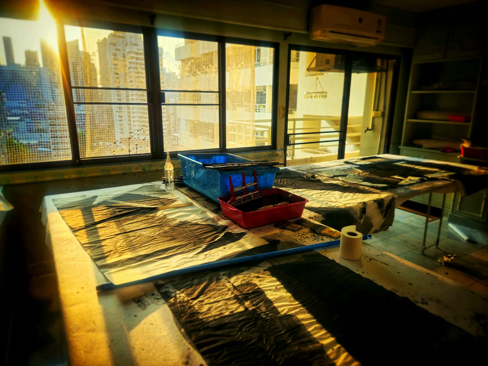Bangkok studio interior: golden light through windows, work in progress on the table